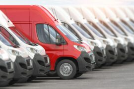 Red delivery van in a row of white vans. Best express delivery and shipemt service concept.